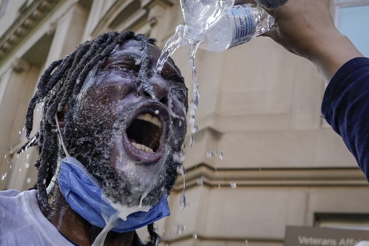 Un manifestante es rociado con agua y leche después de estar expuesto al gas pimienta de la policía durante una protesta el 1 de junio de 2020 en el centro de Washington