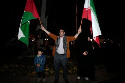 Un manifestante ondea banderas iraníes y palestinas durante una protesta anti-Israel en la Plaza Palestina en Teherán, Irán, la madrugada del domingo 14 de abril de 2024. (AP Foto/Vahid Salemi)