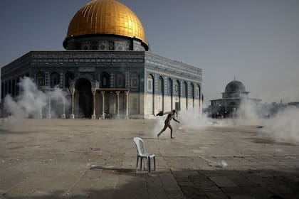 Un manifestante palestino corre entre el gas lacrimógeno lanzado por fuerzas de seguridad israelíes frente a la Cúpula de La Roca en el complejo de la Mezquita de Al-Aqsa, en Jerusalén
