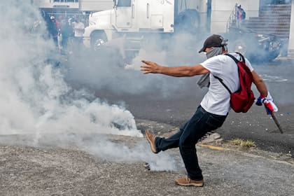 Un manifestante patea un bote de gas lacrimógeno a la policía antidisturbios durante una protesta contra la moción del gobierno de aumentar los impuestos a fin de llegar a un acuerdo crediticio con el FMI, frente a la casa presidencial en San José, el 12 de octubre de 2020
