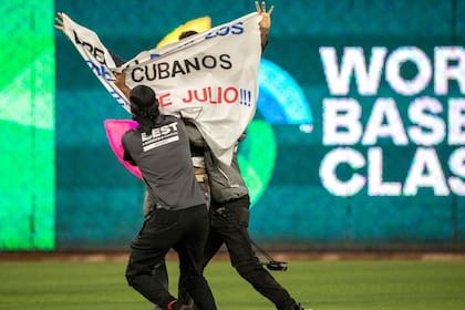 Un manifestante que ingresó al estadio con un cartel contra el régimen cubano es retirado por la seguridad del lugar