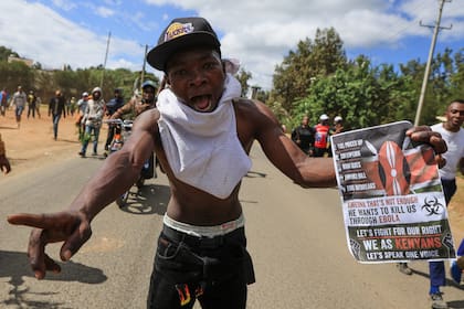 Un manifestante sostiene un cartel durante una protesta contra un centro de cuarentena para ébola en Estados Unidos en la base aérea de Laikipia