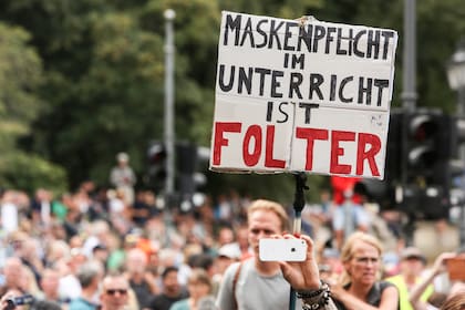 Un manifestante sostiene un cartel que dice "Las máscaras obligatorias durante las lecciones escolares son una tortura", en una protesta no registrada contra las regulaciones gubernamentales sobre el coronavirus celebrada en Berlín, Alemania, el 30 de agosto de 2020