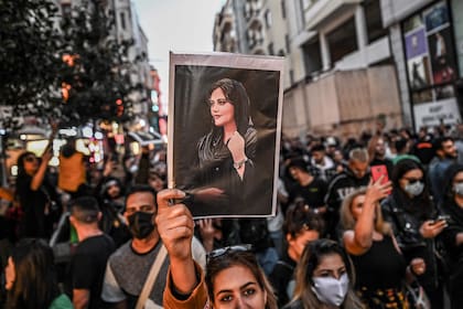 Un manifestante sostiene un retrato de Mahsa Amini durante una manifestación en apoyo de Amini, una joven iraní que murió después de ser arrestada en Teherán por la policía de moralidad de la República Islámica, en la avenida Istiklal en Estambul el 20 de septiembre de 2022. - Amini, 22, estaba de visita con su familia en la capital iraní cuando fue detenida el 13 de septiembre por la unidad policial responsable de hacer cumplir el estricto código de vestimenta de Irán para las mujeres, incluido el uso del velo en público. Fue declarada muerta el 16 de septiembre por la televisión estatal después de haber estado tres días en coma. (Foto de Ozan KOSE / AFP) / AFP FOTOS DEL AÑO 2022