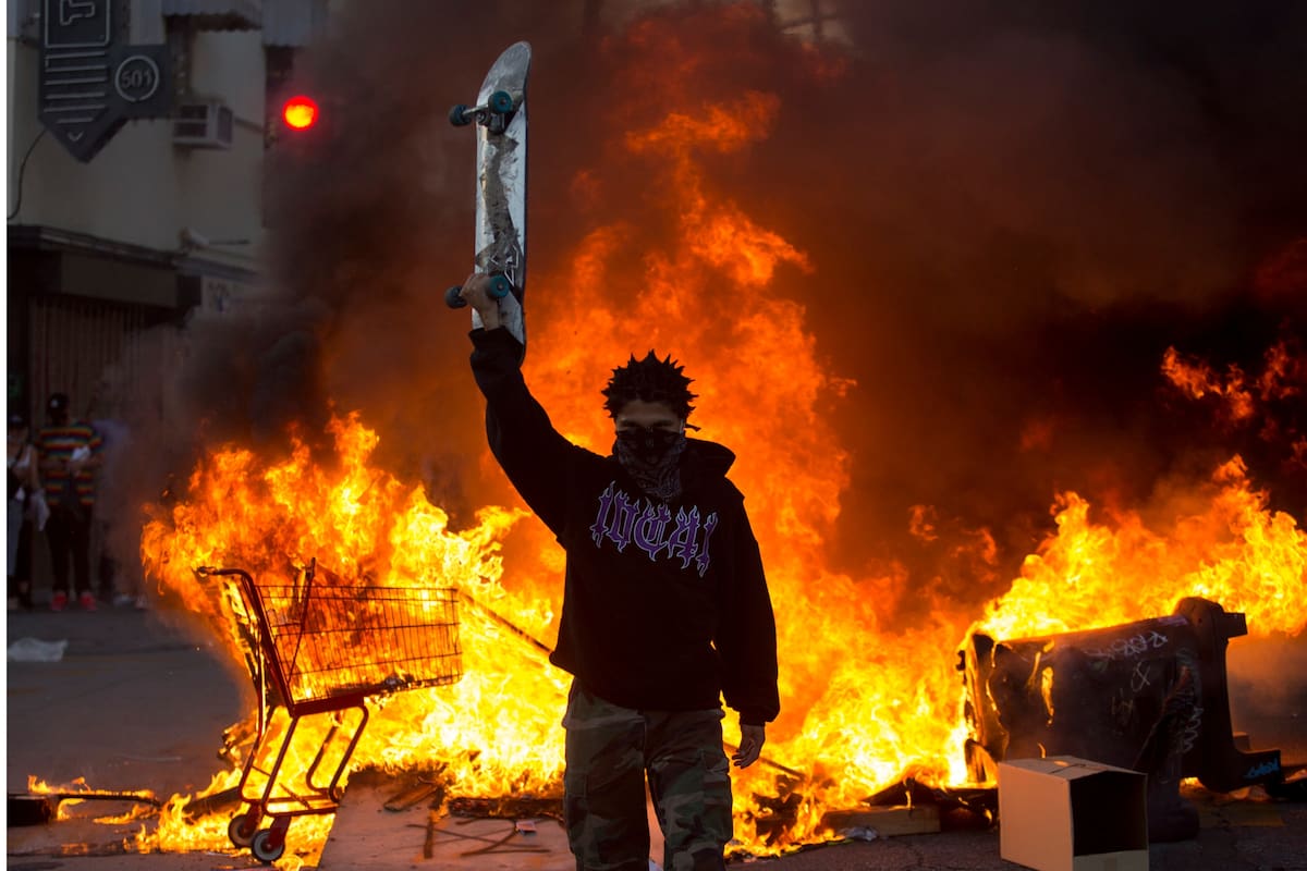 Un manifestante sostiene una patineta frente a un incendio en Los Ángeles, el sábado 30 de mayo de 2020, durante una protesta por la muerte de George Floyd