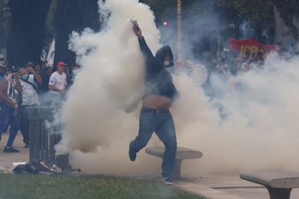 Un manifestante toma un posta de gas y la arroja a la Policía