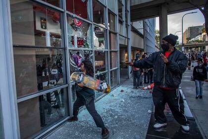 Un manifestante utiliza un shakeboard para destrozar un restaurante en el centro de Los Ángeles el 30 de mayo de 2020 durante una protesta contra la muerte de George Floyd, un hombre negro desarmado que murió mientras era arrestado y clavado en el suelo por la rodilla de un policía de Minneapolis.