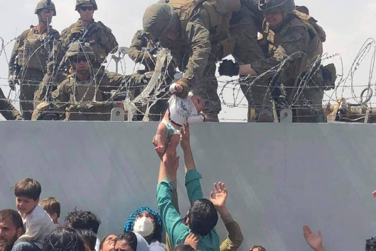 Un marine norteamericano sostiene ayer un bebé que le alcanzan los padres en el aeropuerto de Kabul