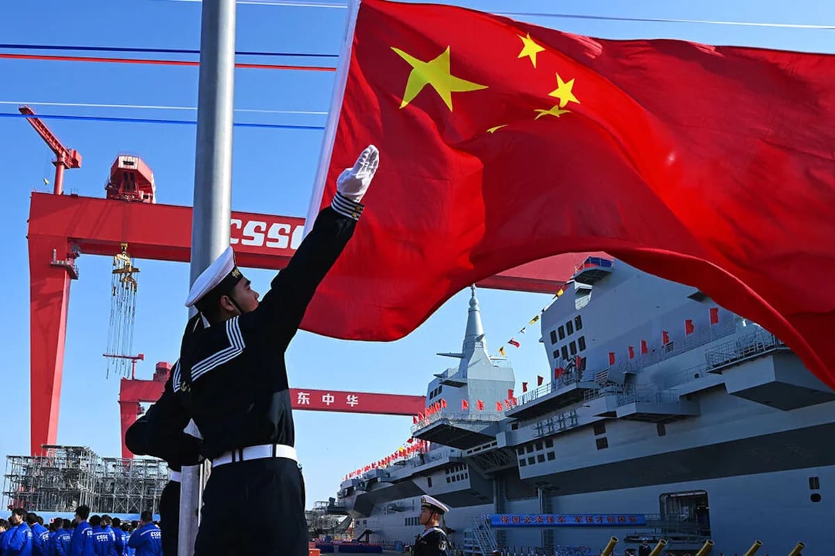 Un marino chino iza la bandera nacional a bordo de un buque de la armada del Ejército Popular de Liberación