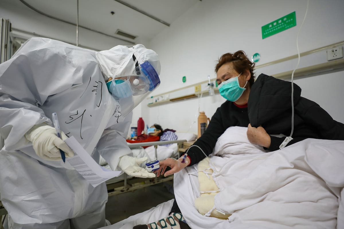 Un médico controla la saturación de oxígeno de un paciente en Wuhan