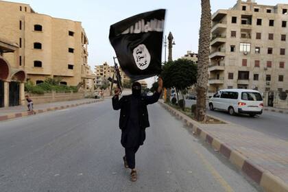 En una calle de Irak, un hombre alza una bandera del Estado Islámico (EI)