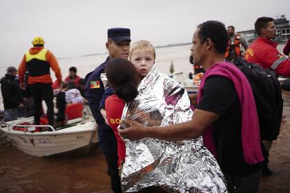 Un miembro de la Defensa Civil carga a un niño rescatado de una zona inundada por fuertes lluvias en Porto Alegre, estado de Rio Grande do Sul, Brasil, el sábado 4 de mayo de 2024.