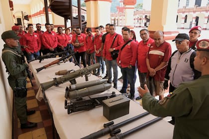 Un miembro de la guardia presidencial venezolana muestra armas a quienes se alistaron para unirse a las milicias civiles durante una campaña nacional de alistamiento convocada por el gobierno del presidente Nicolás Maduro, en el museo militar de Caracas, Venezuela, el sábado 23 de agosto de 2025.