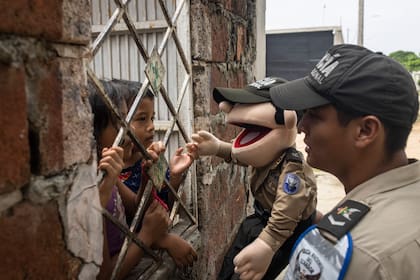Un miembro de la policía comunitaria de Ecuador enseña a los niños sobre seguridad en un barrio bajo el dominio de grupos criminales vinculados al narcotráfico, en Guayaquil, Ecuador, el 31 de mayo de 2023. Ecuador, en el extremo occidental de Sudamérica, se ha convertido en pocos años en la fiebre del oro del narcotráfico, con grandes cárteles de países tan lejanos como México y Albania uniendo fuerzas con bandas callejeras y carcelarias, desatando una ola de violencia sin precedentes en la historia reciente del país. (Victor Moriyama/The New York Times)