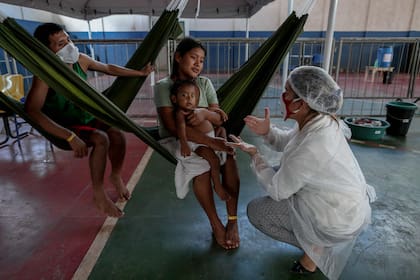 Una trabajadora de la salud atiende a una familia; los médicos se quejan por lo bajo de la falta de insumos mínimos para trabajar
