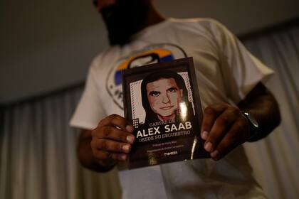 Un miembro del movimiento Liberen a Alex Saab sostiene una imagen de Alex Saab durante una conferencia de prensa en Caracas, Venezuela, el lunes 15 de agosto de 2022. (AP Foto/Ariana Cubillos)