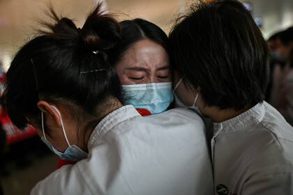 Un miembro del personal médico de la provincia de Jilin llora mientras abraza a enfermeras de Wuhan después de trabajar juntas durante el brote de coronavirus en Wuhan, el 8 de abril de 2020