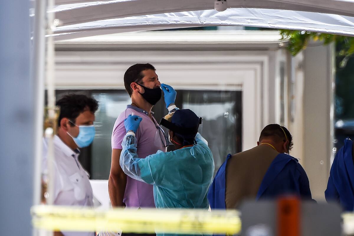 Un miembro del personal médico toma muestras de un hombre en un sitio de prueba de coronavirus "sin cita previa" y "en tránsito" en Miami Beach, Florida, el 24 de junio de 2020