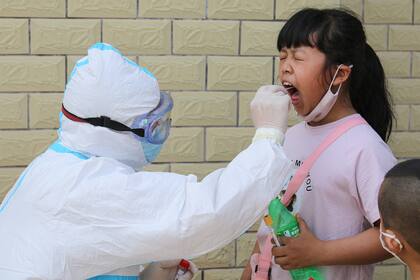 Coronavirus. Un miembro del personal médico toma una muestra de coronavirus a una niña en Jian en la provincia central de Jiangxi de China el 13 de mayo de 2020