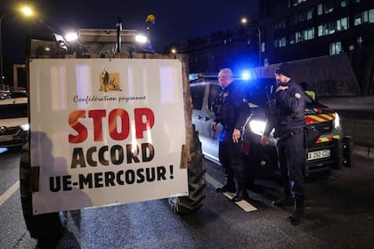 Un miembro del sindicato de agricultores en Francia conduce sus tractores con una pancarta que dice "Alto al Acuerdo UE-Mercosur" mientras participa en de una protesta en la circunvalación de París para presionar al gobierno francés a bloquear el acuerdo comercial con el Mercosur (Photo by Thomas SAMSON / AFP)
