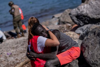 Un migrante es consolado por un miembro de la Cruz Roja española cerca de la frontera de Marruecos y España, en el enclave español de Ceuta