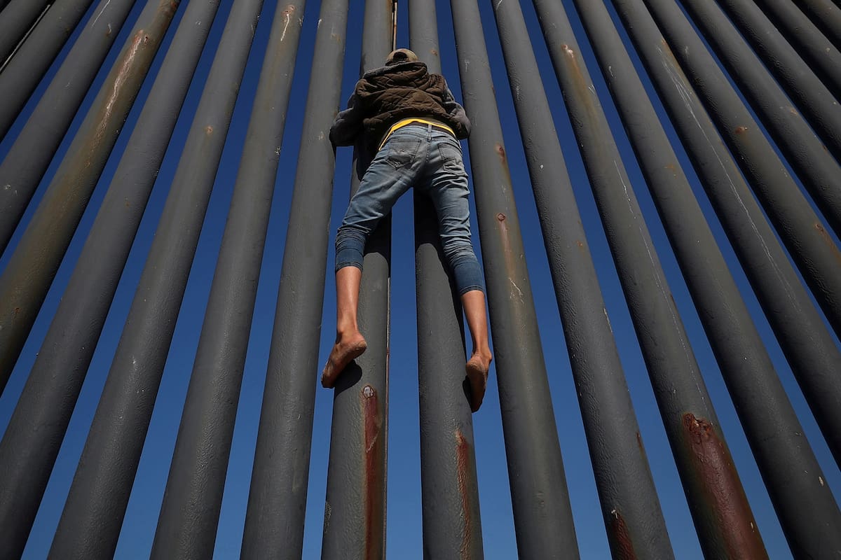 Un migrante, parte de una caravana de miles de habitantes de Centroamérica que intentan llegar a los Estados Unidos, sube la frontera entre México y los Estados Unidos, en Tijuana