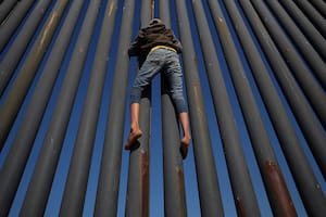 Un migrante, parte de una caravana de miles de habitantes de Centroamérica que intentan llegar a los Estados Unidos, sube la frontera entre México y los Estados Unidos, en Tijuana