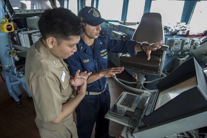 Un militar estadounidense le explica a su par coreano el control de mando del USS John S McCain, que dejará de utilizar pantallas táctiles para volver a utilizar los controles tradicionales basados en botones y perillas