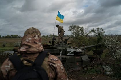 Un militar ucraniano camina sobre un tanque ruso destruido cerca de la frontera con Rusia, en Kharkiv