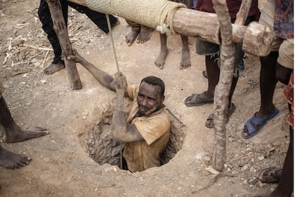 Un minero surge del agujero de la mina informal de zafiro