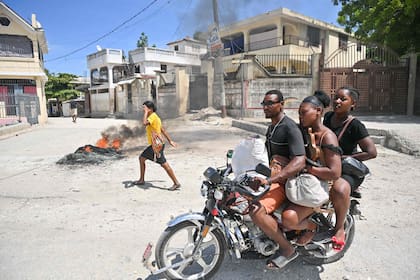 Un motociclista pasa junto a neumáticos ardiendo mientras las personas protestan por el aumento del costo de vida en Petit-Goave, Haití, el 14 de septiembre de 2023.