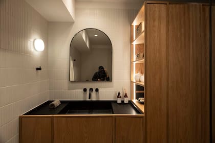 Un mueble de roble americano con paneles lisos y ranurados, con tiras LED y espejo sin marco.