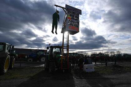 Un muñeco cuelga de un tractor, durante una manifestación en la frontera franco-alemana en Ottmarsheim, este de Francia, el 1 de febrero de 2024, como parte de protestas a nivel nacional convocadas por varios sindicatos de agricultores sobre salarios, impuestos y regulaciones. (Foto de PATRICK HERTZOG / AFP)