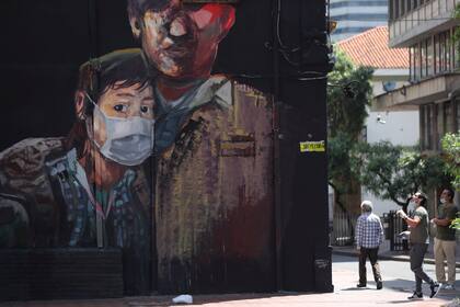 Un mural muestra a una joven portando una mascarilla, en Bogotá, Colombia, el lunes 13 de abril de 2020. (AP Foto/Fernando Vergara)