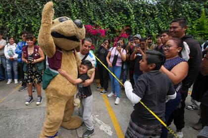 Un niño abraza a Wisin el "perrito luchador" en una función de lucha libre en el Instituto de la Juventud, el jueves 25 de julio de 2024, en Ciudad de México. (AP Foto/Fernando Llano)