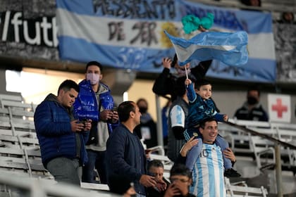 Un niño agita una bandera argentina, sentado en los hombros de su padre