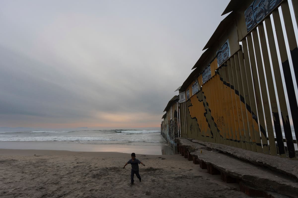 Un niño camina cerca del muro que separa a Estados Unidos y México en el océano Pacífico, el martes 26 de noviembre de 2024, en Tijuana, México. (AP Foto/Gregory Bull)