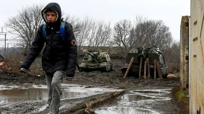 Un niño camina con dos tanques a su espalda