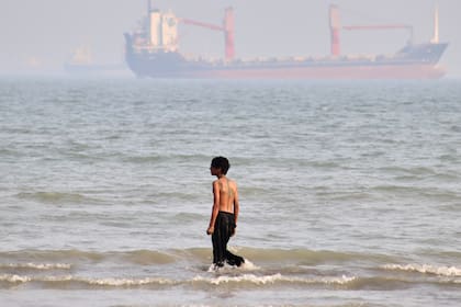 Un niño camina por la orilla mientras buques comerciales están fondeados en el estrecho de Ormuz, ante la costa de Bandar Abbas, Irán, el 31 de agosto de 2026. (Razieh Poudat/ISNA vía AP)