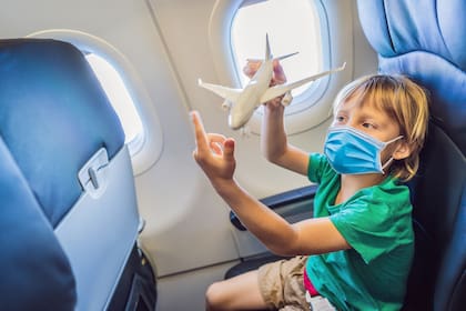 Un niño con mascarilla en un avión, como parte de las medidas de prevención contra el coronavirus