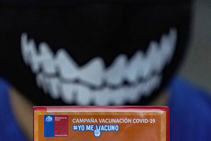 Un niño muestra su cartilla de vacunación luego de recibir una dosis de la vacuna contra el COVID-19 en su escuela en Santiago, Chile, el lunes 27 de septiembre de 2021, durante el inicio de la inmunización en escuelas para niños de entre 6 y 11 años. (AP Foto/Esteban Felix)