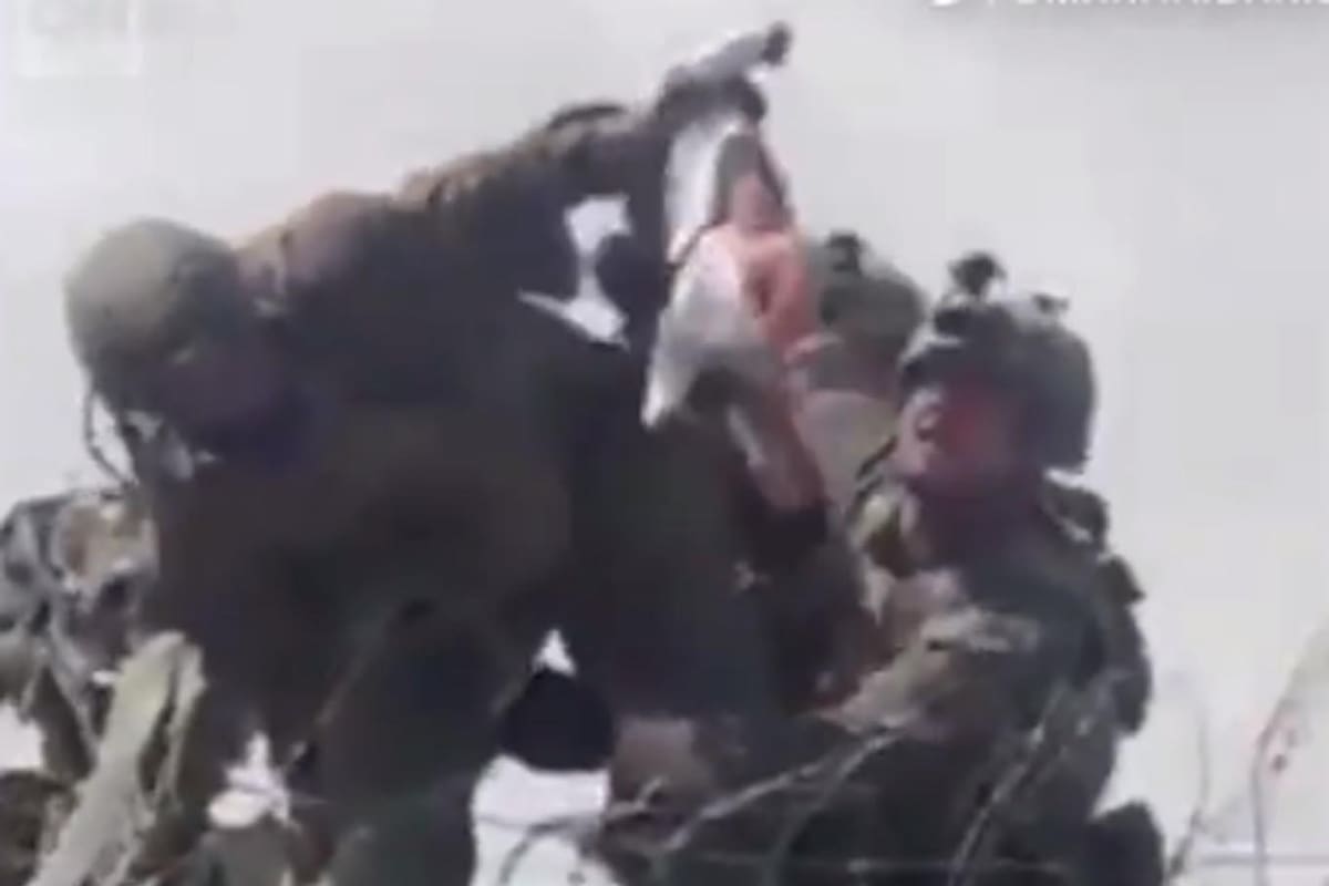 Un niño pequeño es entregado sobre el muro del aeropuerto de Kabul a las tropas estadounidenses.