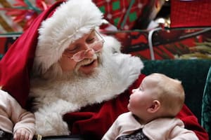 Un niño quiso llamar la atención de su madre mientras posaba con Papá Noel, pero su pedido de ayuda no surtió efecto (Foto AP/ Robert F. Bukaty)