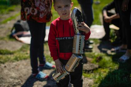 Un niño sostiene un tren de juguete en el exterior de su casa, que sufrió graves daños tras un ataque ruso en Pokrovsk, en el este de Ucrania, el 25 de mayo de 2022. (AP Foto/Francisco Seco)