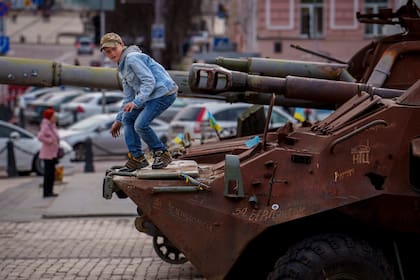 Un niño trepa en un oxidado vehículo de transporte de personal, parte de una muestra de equipo militar ruso destruido en Kiev (Archivo)