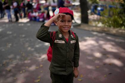 Un niño vestido como el difunto presidente Hugo Chávez saluda mientras hace fila para visitar la tumba de Chávez durante las conmemoraciones por el 10mo aniversario de su muerte, el domingo 5 de marzo de 2023, fuera del Cuartel de la Montaña 4F, en Caracas. (AP Photo/Ariana Cubillos)