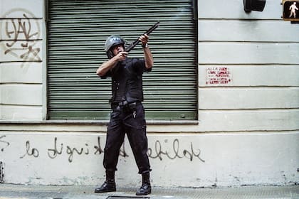 Un oficial abre fuego sobre las ventanas de un edificio el 20 de diciembre de 2001, en los alrededores de la Plaza de Mayo