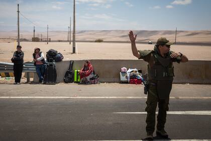 Un oficial de policía dirige el tráfico en el cruce fronterizo de Chacalluta en Arica, Chile, mientras los migrantes esperan para cruzar a Perú