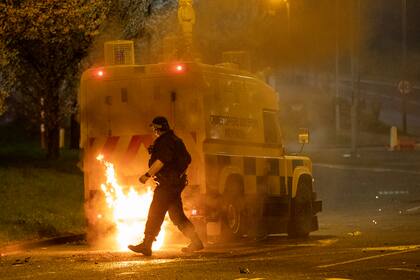 Un oficial de policía rodea un vehículo policial en llamas, en Newtownabbey, al norte de Belfast, en Irlanda del Norte