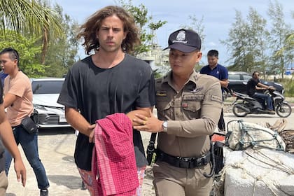 Un oficial de policía tailandés escolta al español Daniel Sancho Bronchalo, acusado de asesinar y desmembrar a un cirujano colombiano, desde la isla de Koh Phagnan hasta el tribunal de la isla de Koh Samui, en el sur de Tailandia, el lunes 7 de agosto de 2023.